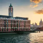 OXO Tower on London's South Bank at sunset, with the River Thames in the foreground and St Paul's Cathedral across the river
